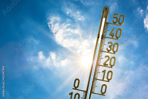 Hitzewelle, Thermometer mit strahlender Sonne und blauem Himmel im Hintergrund