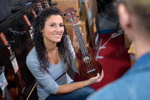 beautiful girl holding a guitar in a musical shop