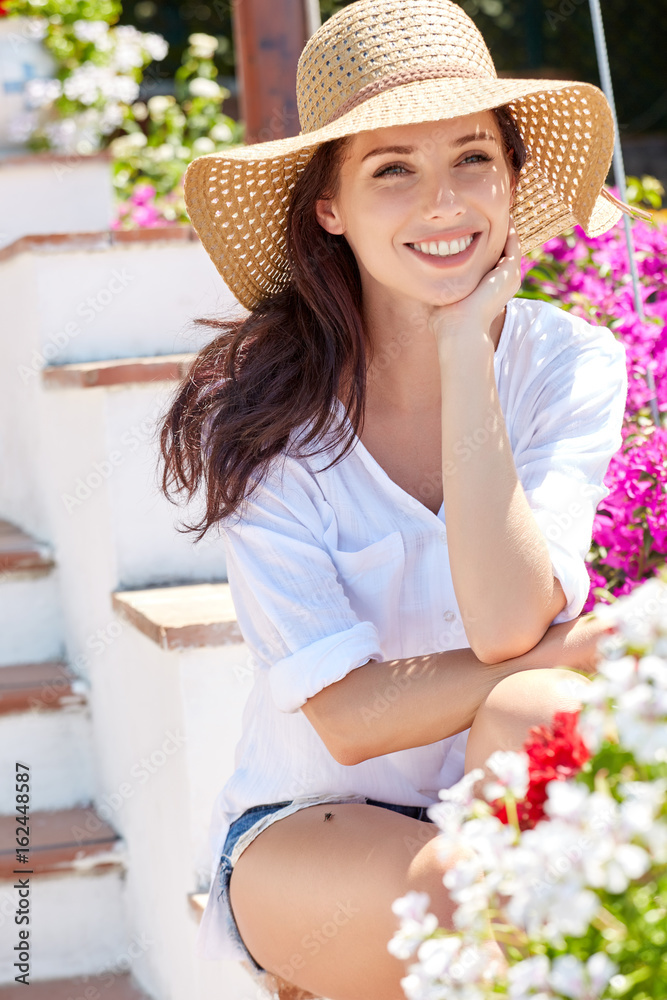 Young pretty woman smiling. Beautiful women in a straw hat at the summer garden.