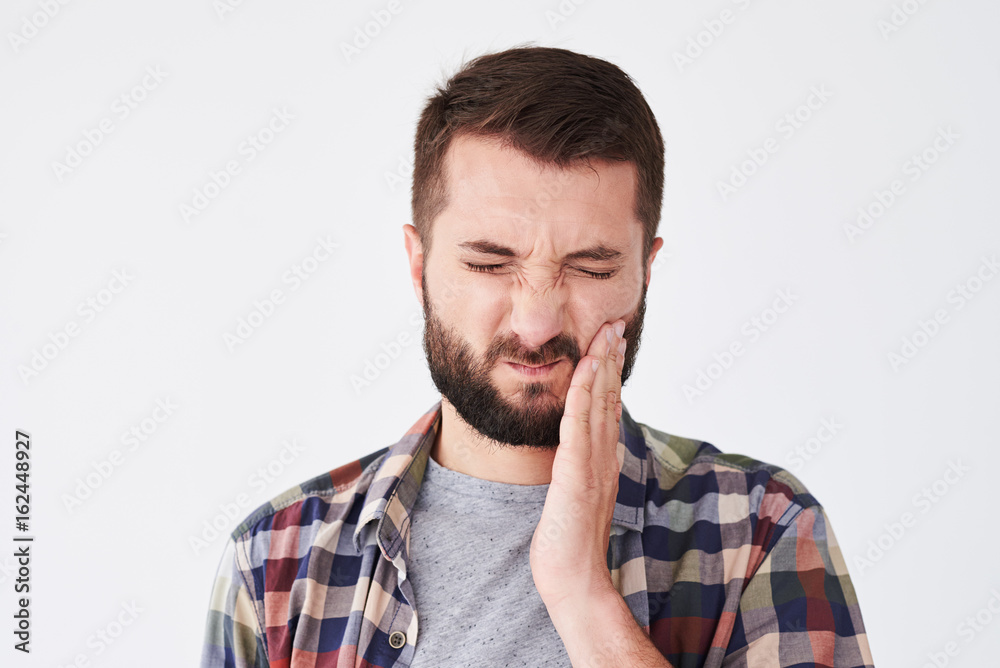 Sad bearded young man suffering from toothache