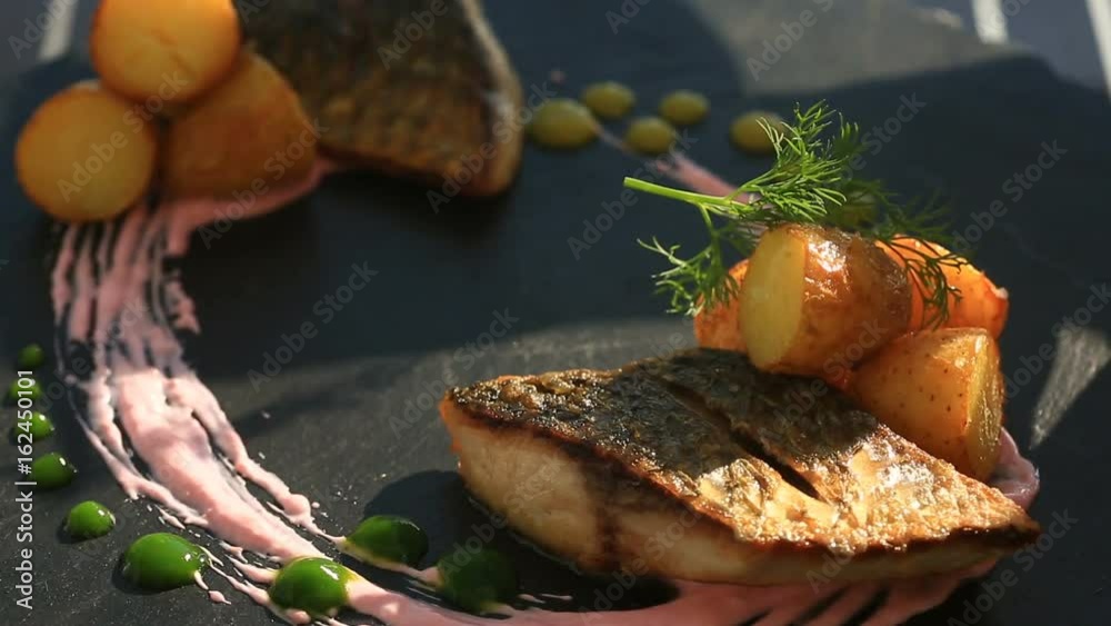 A dish of haute cuisine. close-up. Fish with young potatoes. mullet. With a glass of white wine. Primorsik restaurant with a view to the sea.