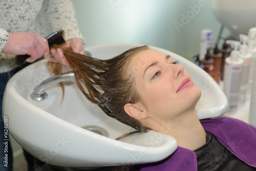 beautiful woman is getting a hairwash by a hairdresser