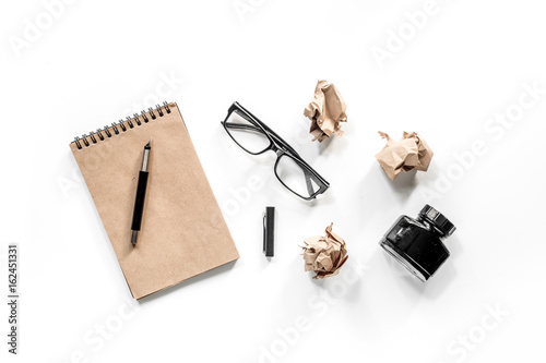 Writer concept. Vintage notebook, crumpled paper and glasses on white background top view