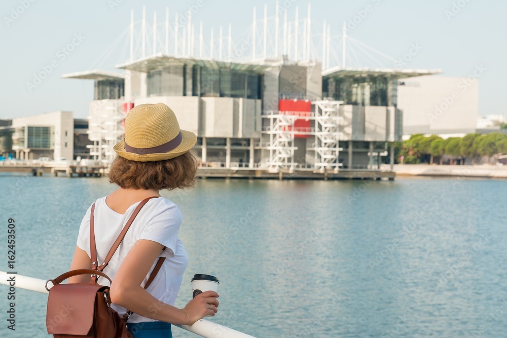 Attractive young woman make photo near Lisbon Oceanarium near river Tagus