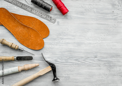 Working place of shoemaker. Skin and tools on grey wooden desk background top view