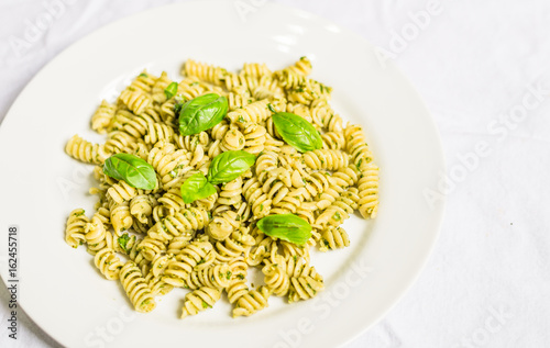 Pasta with basil and cheese pesto against white background