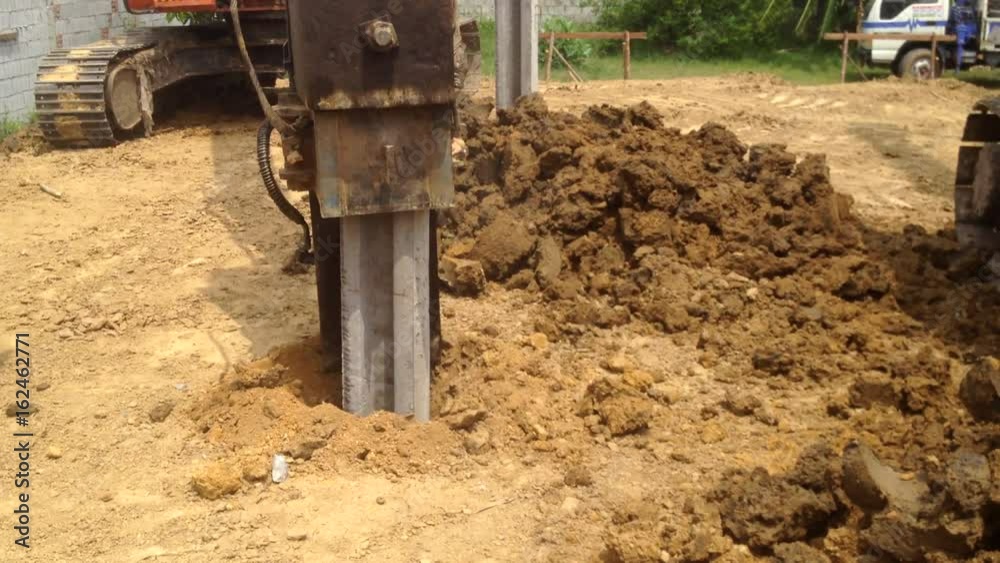 Backhoe with a hammer steel piles device at construction site pile foundation