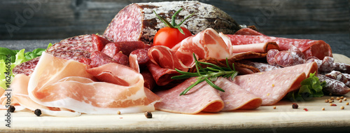 Food tray with delicious salami, pieces of sliced ham, sausage, tomatoes, salad and vegetable - Meat platter with selection