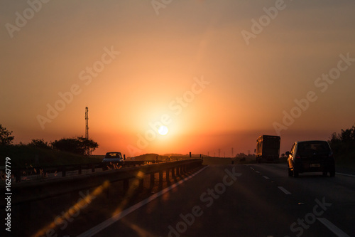 Photo of cars and truck on road at sunset