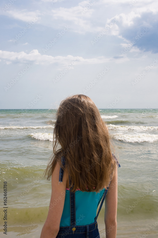 Young girl with long blond hair on the sea coast Young girl with long blond hair on the sea coast