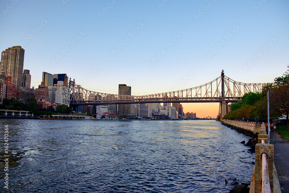 Queensboro bridge going over East River with an autumn sunset in the background