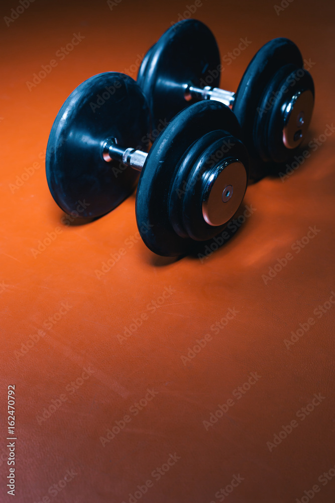 Photo of dumbells on a gym floor. Dumbells with centered light. Focus in center. Photo of dumbells on a gym floor. Dumbells with centered light. Focus in center.