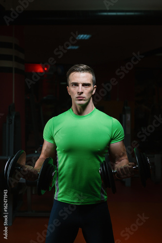 Closeup portrait of a muscular man workout with barbell at gym. Deadlift barbells workout.