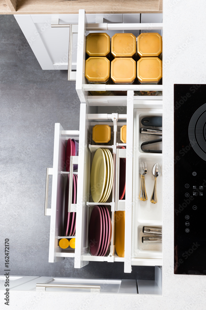 Top view of organized kitchen drawers and electric kitchen stove. Modern kitchen organization of