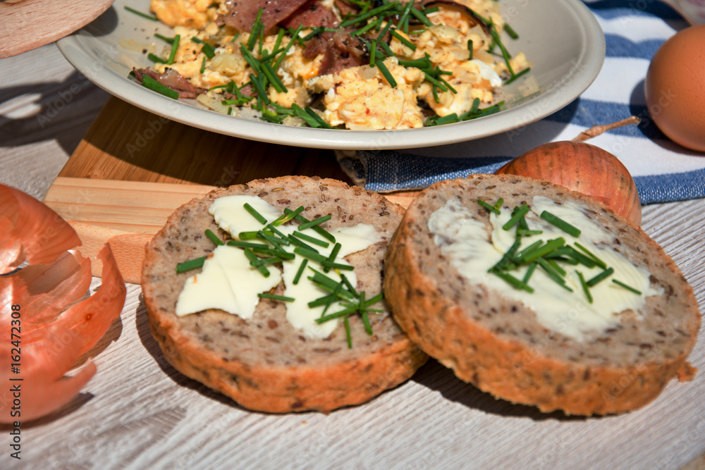 Čerstvá snídaně z domacích vajec, cibule a smažené šunky, prostřeno na dřevěném stole