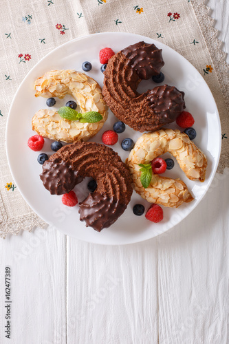 Almond and chocolate cookies in the shape of a horseshoe with fresh berries close-up. vertical top view