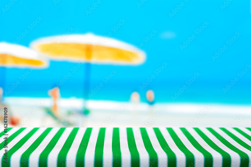 Table top covered with striped tablecloth on blurred summer beach background