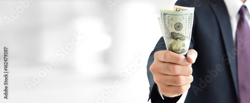 Businessman holding money,   united states dollar (USD) bills, on blur white gray background