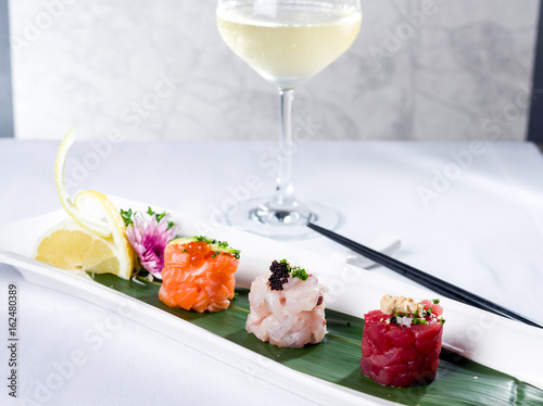 Mini raw fish sushi style with tuna, seabass and salmon with a glass of white wine