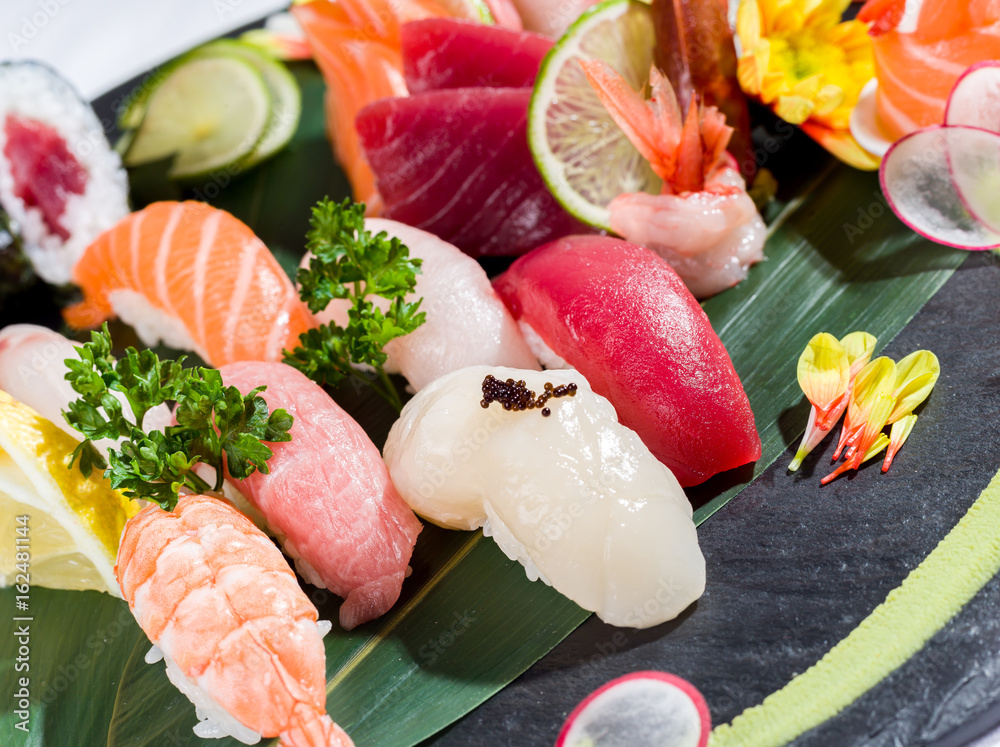 Mix of sushi and sashimi on a black dish, close up