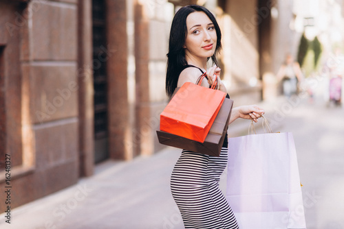 Fashionably dressed woman with colored shopping bags, shopping concept