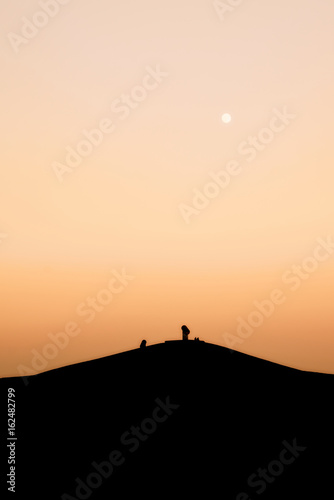 Halde in Gelsenkirchen mit zwei Menschen auf dem Gipfel w  hrend Sonnenuntergang