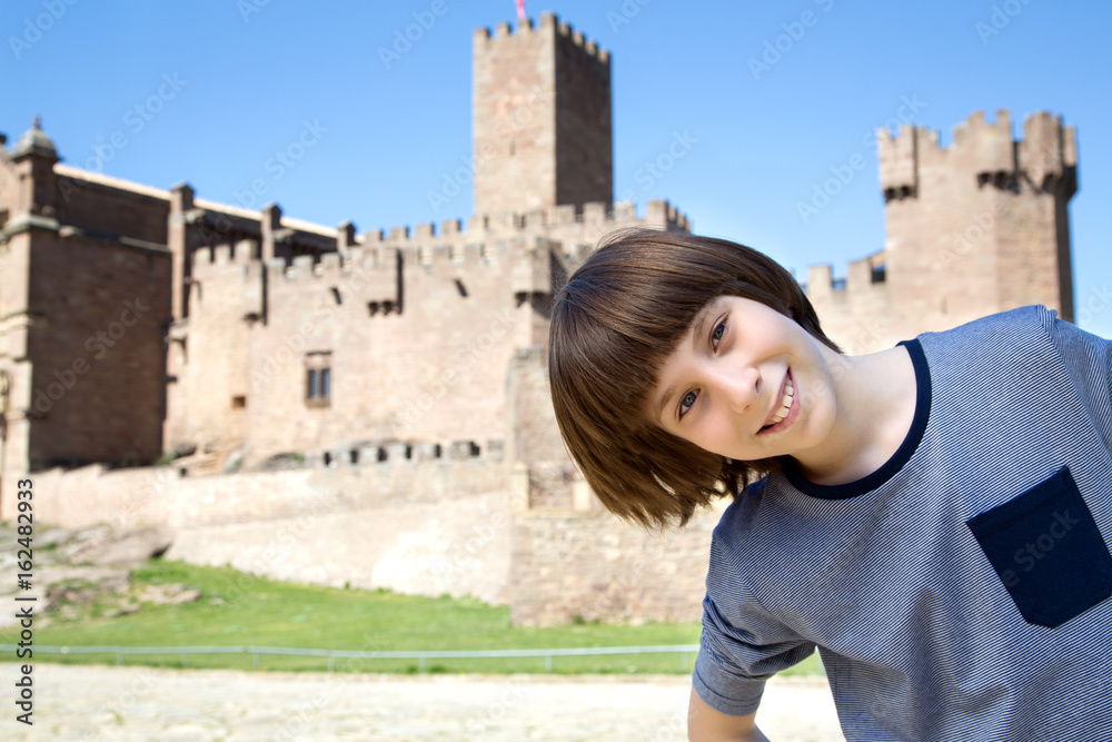 Beautiful 11 years old boy posing and smiling over ancient spanish castle Javier, Navarre, Spain. Cultural and historical spanish heritage. Young tourist making selfie agains architectural sight
