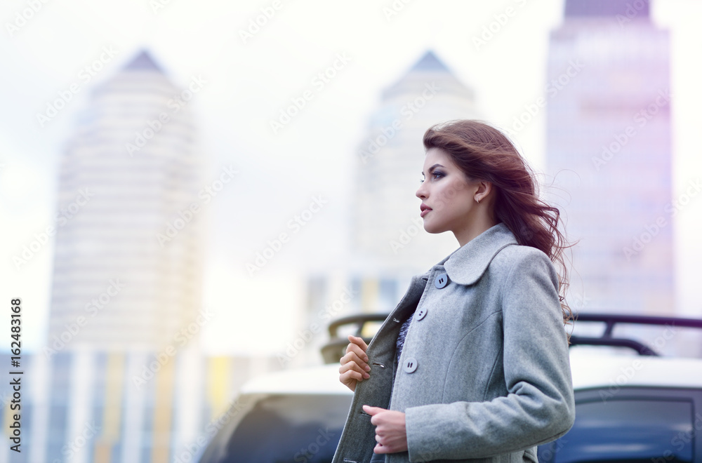 Fototapeta premium Young pretty girl, spring outdoor portrait. Beautiful woman runing against the backdrop of the urban landscape