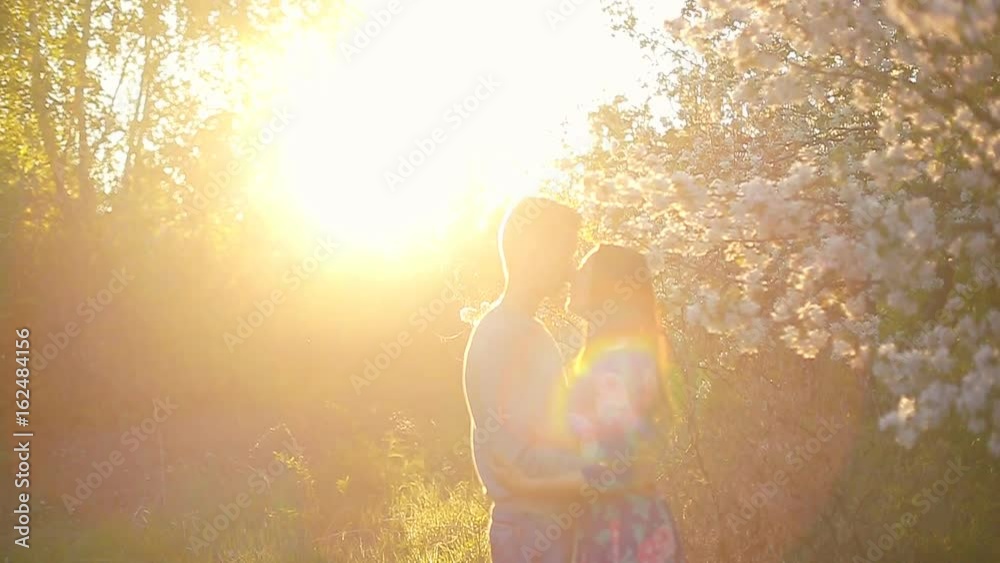 Loving boyfriend and girl in the summer garden at sunset Loving boyfriend and girl in the summer garden at sunset