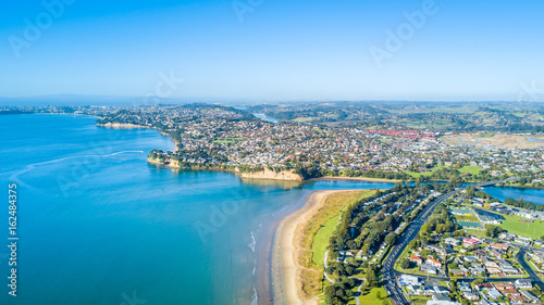 Aerial view on sunny beach with residential suburb on the background. Auckland, New Zealand. © Dmitri