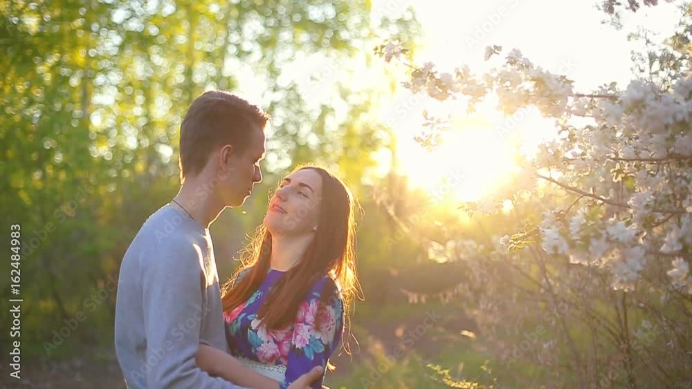 Loving boyfriend and girl in the summer garden at sunset Loving boyfriend and girl in the summer garden at sunset