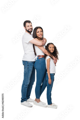 side view of cheerful multiethnic family hugging and standing in line together isolated on white