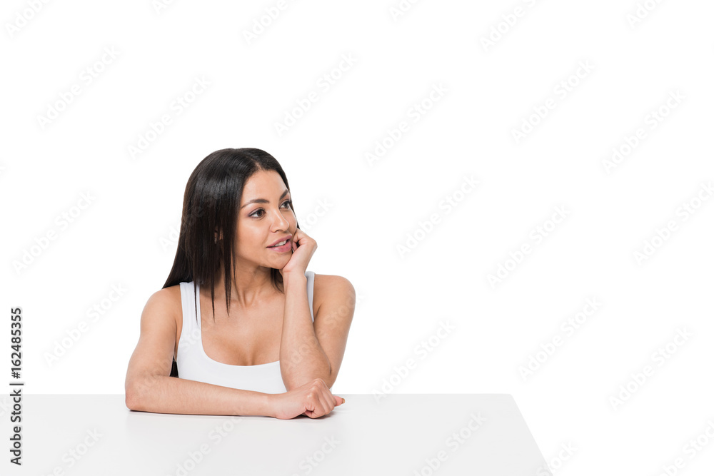 Beautiful young woman sitting at table and looking away isolated on white Beautiful young woman sitting at table and looking away isolated on white
