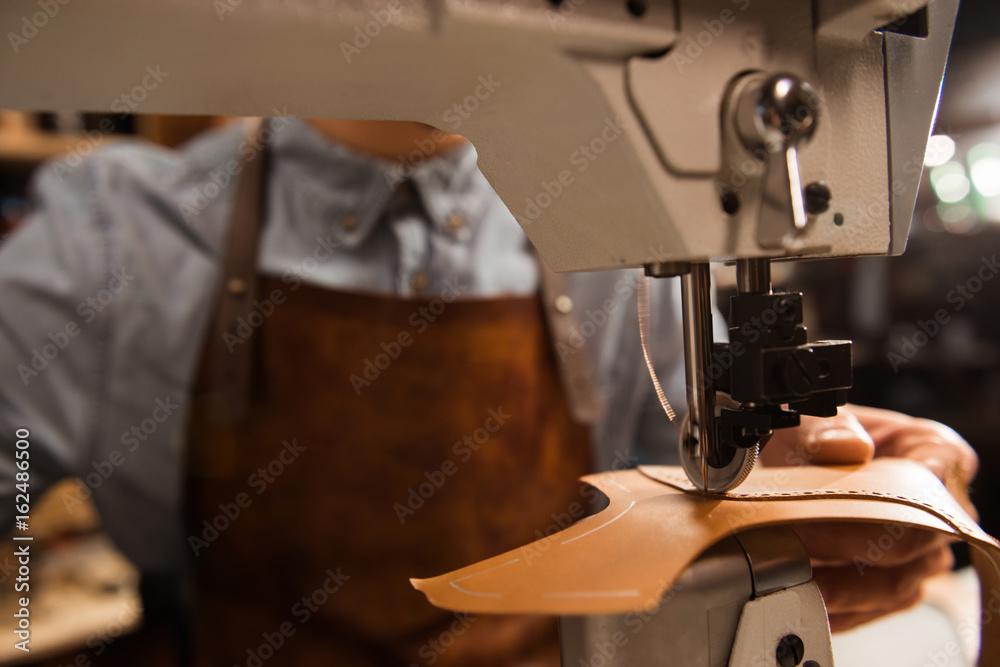 Fototapeta premium Close up of a cobbler using sewing machine