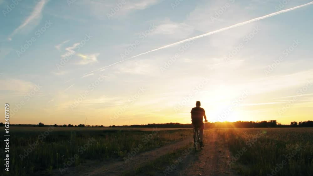 Cycling at sunset, the sun's rays, dirt road training on the bike Cycling at sunset, the sun's rays, dirt road training on the bike