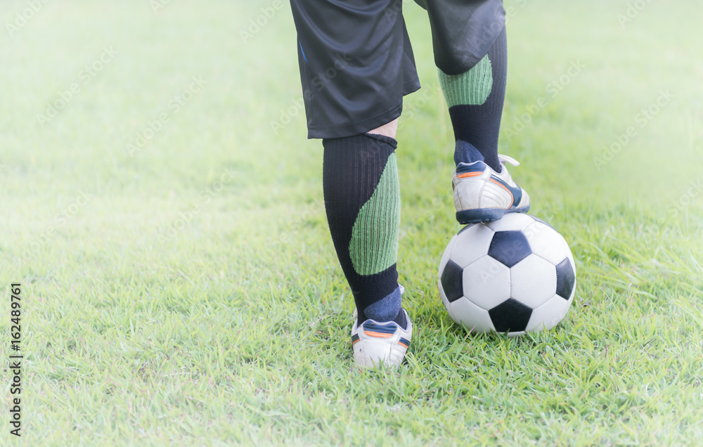 soccer ball with child feet player on green grass