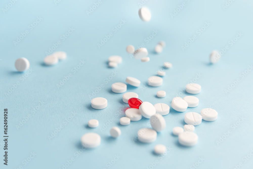 Close up of fallen white tablets with one red capsule Close up of fallen white tablets with one red capsule