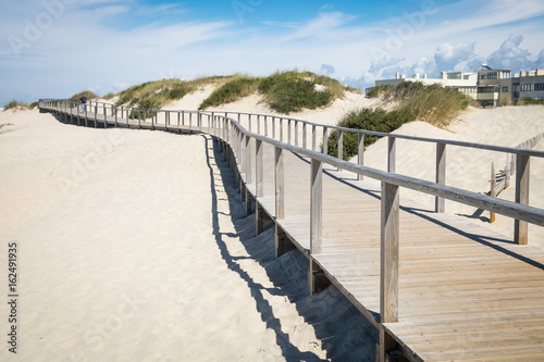 Wooden promenade at european sandy beach near sea with running man, Beach in portugal, Jogging trail, Sand dunes with a wooden footbridge for pedestrians