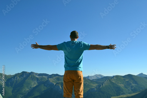 Silhouette man with hands rise up on beautiful view, upon the top of mountain. Concept freedom of life.