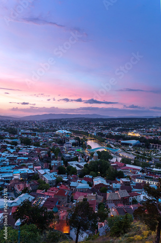 Sunset view of Tbilisi, capital of Georgia country, from Narikala fortress. Famous landmarks - Presidential Administration, Bridge of Peace with illumination.
