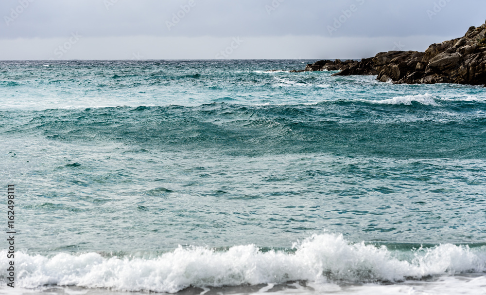 Strong wind, sea waves and the coast or beach.