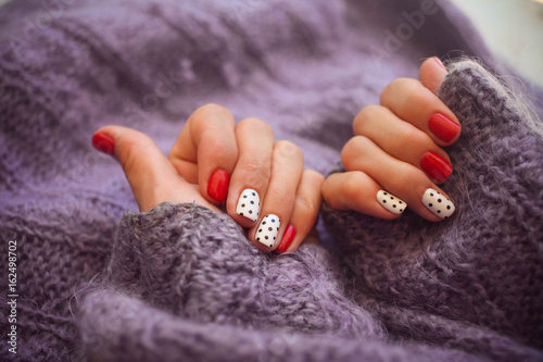 Woman hands with beautiful winter trend knit sweater manicure