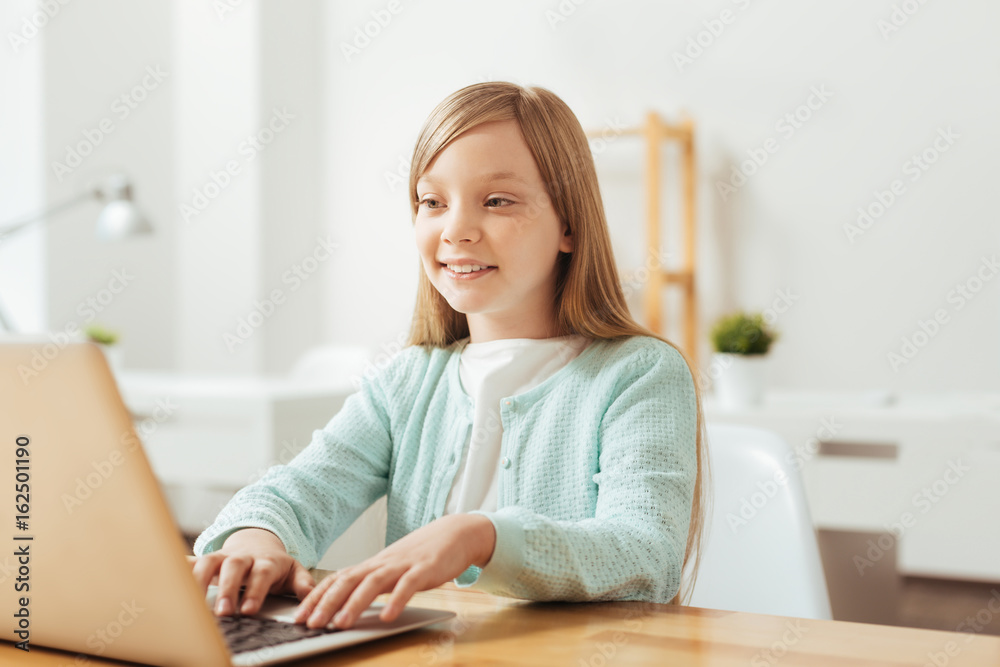 Bright energetic child typing something on her laptop Bright energetic child typing something on her laptop