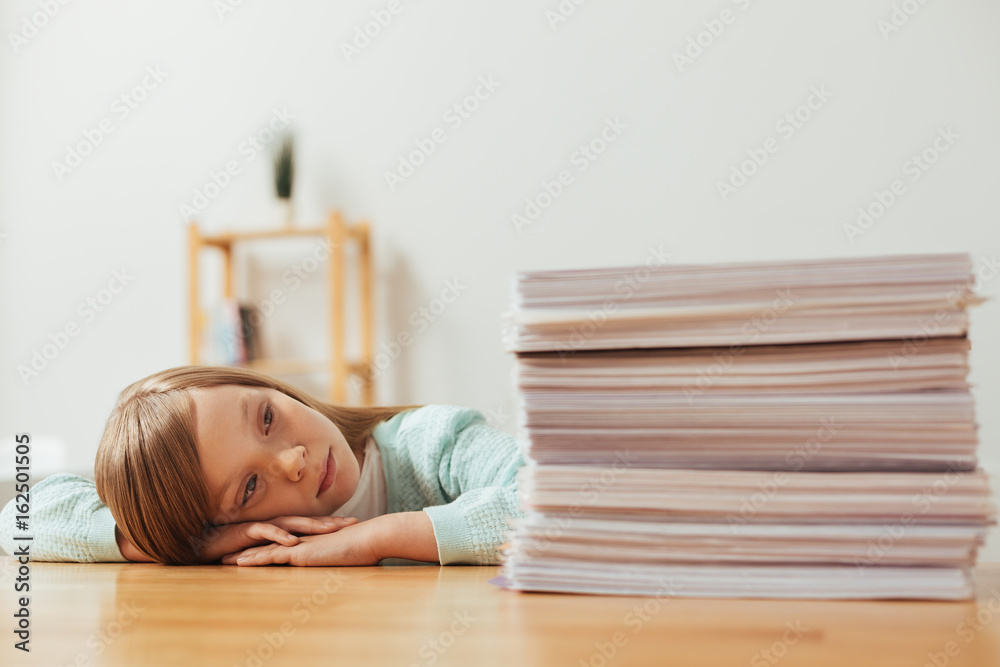 Tired diligent student looking at the pile of papers Tired diligent student looking at the pile of papers