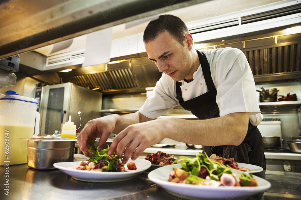 Chef adding salad garnish to plates of food Chef adding salad garnish to plates of food