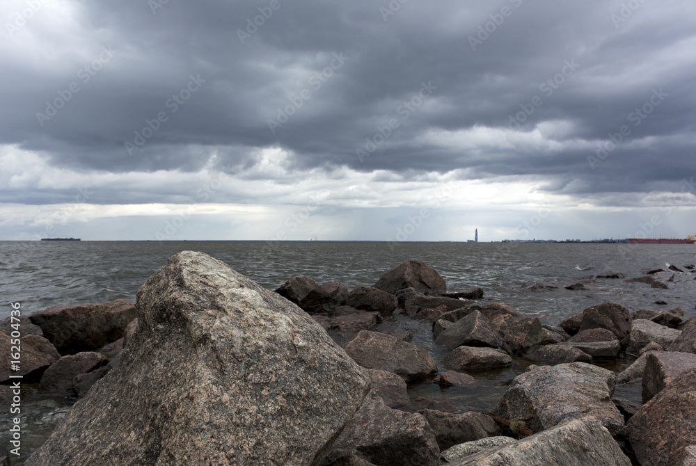 stones, boulders in the water, the Gulf coast, rain clouds in the sky
