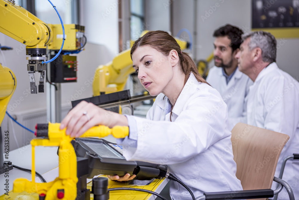 Engineers examining industrial robots Engineers examining industrial robots