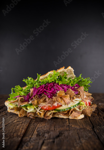 Close up of kebab sandwich on old wooden table.