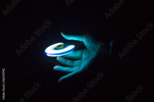 Play Fidget spinner spinning and Hand on dark background With Ligtht photo