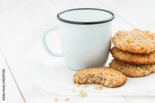 Cookies and a cup on a light wooden table on a white background closeup.